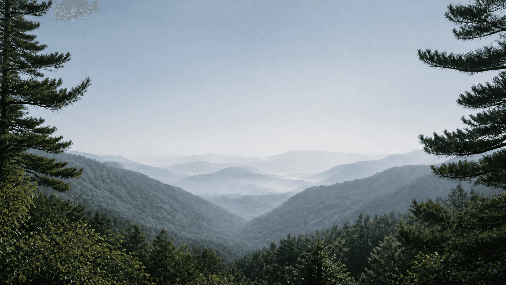 Layered mountain ridges receding through a quiet forest valley